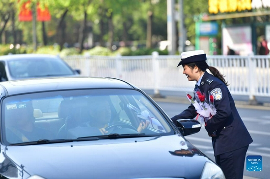 A traffic police officer sends flowers to a driver who stops politely to allow pedestrians to cross in Liuzhou, south China's Guangxi Zhuang Autonomous Region, Dec. 2, 2021. Dec. 2 marks the national traffic safety day in China. An event was held in Liuzhou to promote traffic safety. (Xinhua/Huang Xiaobang) 