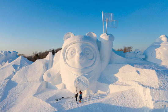 Aerial photo taken on Dec. 27, 2021 shows workers finishing the main snow sculpture featuring Beijing 2022 mascots at the 34th Harbin Sun Island International Snow Sculpture Art Exposition in Harbin, northeast China's Heilongjiang Province. (Xinhua/Xie Jianfei)