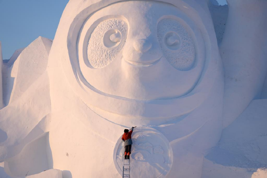 A worker finishes the main snow sculpture featuring Beijing 2022 mascots at the 34th Harbin Sun Island International Snow Sculpture Art Exposition in Harbin, northeast China's Heilongjiang Province, Dec. 27, 2021. (Xinhua/Wang Jianwei)