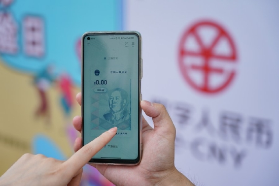 A staff member of the Bank of Communications demonstrates the use of the online wallet of digital RMB at the Happy Valley Beijing theme park the in Beijing, capital of China, June 16, 2021. (Xinhua/Chen Zhonghao)