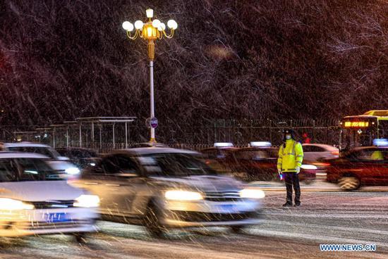 A police officer is on duty amid snowfall in Urumqi, capital of northwest China's Xinjiang Uygur Autonomous Region, Nov. 19, 2019. Days of continuous snowfall has left streets wet and slippery in the city of Urumqi. (Xinhua/Wang Fei)