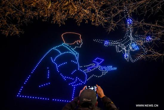 A citizen takes photos of a drone light display at a park in Changchun, northeast China's Jilin Province, Oct. 14, 2020. A light display featuring 1,000 drones was held on Wednesday as a part of the 2020 Changchun International UAV Industrial Expo. The light display will be held every night from Oct. 14 to 16. (Xinhua/Yan Linyun)