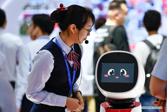 A staff member reacts with a robot at the fifth World Intelligence Congress at Tianjin Meijiang Conference and Exhibition Center in north China's Tianjin, May 23, 2021. The fifth World Intelligence Congress, a major artificial intelligence (AI) event in China, kicked off in north China's Tianjin Municipality on Thursday, highlighting frontier AI technologies and applications. The four-day event, with the theme of "New Era of Intelligence: Empowering New Development, Fostering New Pattern," has attracted the participation of over 240 AI companies and institutions. (Xinhua/Sun Fanyue)