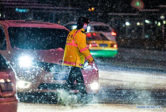 A police officer is on duty amid snowfall in Urumqi, capital of northwest China's Xinjiang Uygur Autonomous Region, Nov. 19, 2019. Days of continuous snowfall has left streets wet and slippery in the city of Urumqi. (Xinhua/Wang Fei)