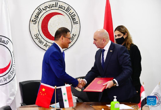 Chinese Ambassador to Syria Feng Biao (L) shakes hands with Khaled Hboubati, the head of the Syrian Arab Red Crescent (SARC), after signing a delivery note for the food aid in Damascus, Syria, on Jan. 16, 2022. (Photo by Ammar Safarjalani/Xinhua)