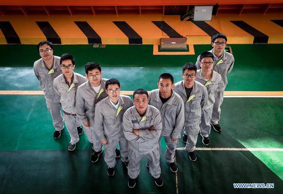 Qiao Sukai (C) poses for a photo with his team members at a training center in Shenzhen, south China's Guangdong Province, Nov. 20, 2019. Every 18 months, the Dayawan Nuclear Power Plant has to undergo a fuel assemblies replacement, which is one of the most important moments for the nuclear power plant. Dozens of engineers are divided into four shifts and operate the equipment day and night when the reactor is shut down. Their leader, Qiao Sukai, has been dealing with nuclear fuel since July 1993 when the nuclear fuel assembly of Dayawan Nuclear Power Plant arrived. The professional and technical maintenance team led by Qiao is responsible for the maintenance of nuclear fuel for more than half of the nuclear power units in the country. Qiao and his team have successfully operated fuel installing and uninstalling more than 170 times without making a single mistake. (Xinhua/Mao Siqian)