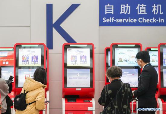 Passengers perform self-service check-in process at Terminal 2 building of the Shanghai Pudong International Airport in east China's Shanghai, Nov. 24, 2020. The airport's recent daily throughput maintains at around 1,000 flights, with passengers wearing face masks and orderly moving in and out. (Xinhua/Ding Ting)