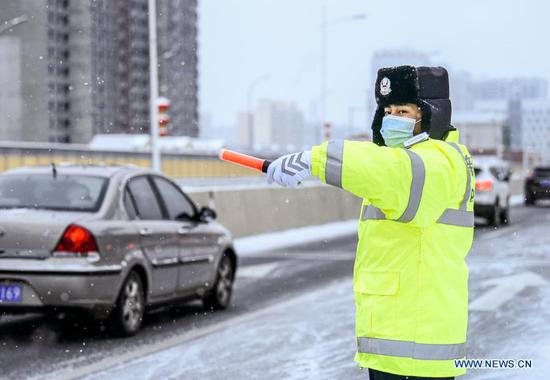 A police officer is on duty amid snowfall in Urumqi, capital of northwest China's Xinjiang Uygur Autonomous Region, Nov. 19, 2019. Days of continuous snowfall has left streets wet and slippery in the city of Urumqi. (Xinhua/Wang Fei)