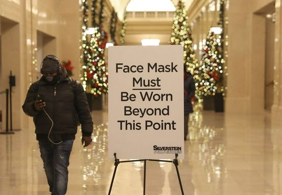 A man walks past a notice of wearing face masks at a building in New York, the United States, Dec. 2, 2021. (Xinhua/Wang Ying)