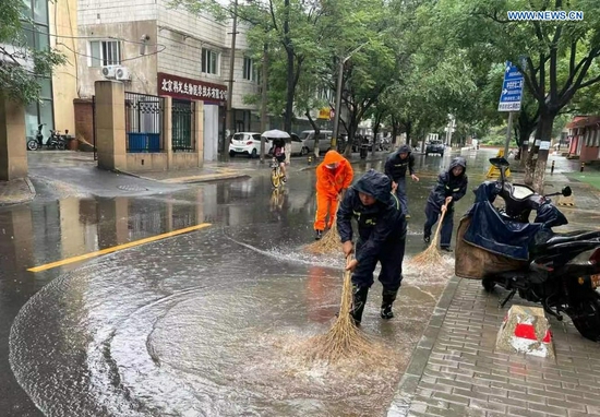 Photo taken with a mobile phone on July 18, 2021 shows community workers cleaning a waterlogged street after rainstorms hit Haidian District in Beijing, capital of China. The Beijing Meteorological Observatory on Sunday morning issued an orange warning for rainstorms after the accumulated rainfall in some areas of the capital had exceeded 150 mm. (Xinhua)