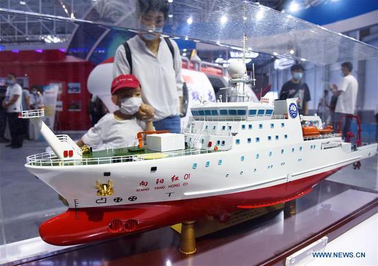 Visitors watch the model of Xiangyanghong 01, China's elite scientific research ship, during the 2020 East Asia Marine Expo in Qingdao, east China's Shandong Province, Sept. 22, 2020. The 2020 East Asia Marine Expo opened Tuesday in Qingdao, a coastal city of east China's Shandong Province, convening more than 770 companies and institutes from over 70 countries and regions. More than 50,000 different exhibits ranging from ocean engineering, offshore oil and gas exploration, seabed exploration, deep-sea aquaculture and scientific research equipment, to scientific achievements in marine surveying and mapping as well as fishery products have been put on show at the six-day expo, which boasts 60,000 square meters of exhibition area. (Xinhua/Li Ziheng)