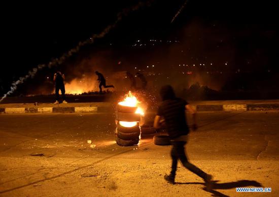 Protesters run to take cover from tear gas canisters fired by Israeli soldiers at Huwwara checkpoint near the West Bank city of Nablus, on May 10, 2021. Tension between Israelis and Palestinians has been flaring up over the past few days amid the escalating violence in East Jerusalem between Palestinian demonstrators and Israeli forces. (Photo by Ayman Nobani/Xinhua)