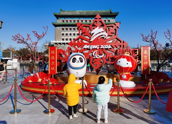 Photo taken on Jan. 16, 2022 shows children looking at street decorations for the Beijing 2022 Olympic and Paralympic Winter Games before the upcoming Chinese Lunar New Year in Beijing, capital of China. (Xinhua/Zhang Chuanqi)