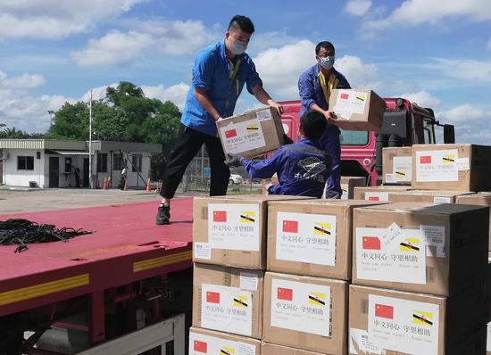 People unload medical materials donated by China in Bandar Seri Begawan, Brunei, April 23, 2020. (Photo by Jeffrey Wong/Xinhua)