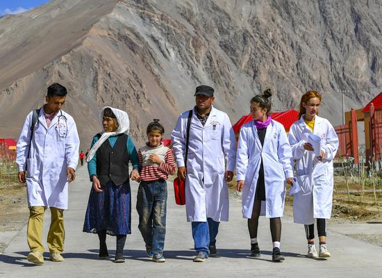 Doctors are seen on their way to provide diagnosis and treatment services at the resettlement community for relocated residents of Rasekam Village in Taxkorgan Tajik Autonomous County, northwest China's Xinjiang Uygur Autonomous Region, July 7, 2019. (Xinhua/Wang Fei)