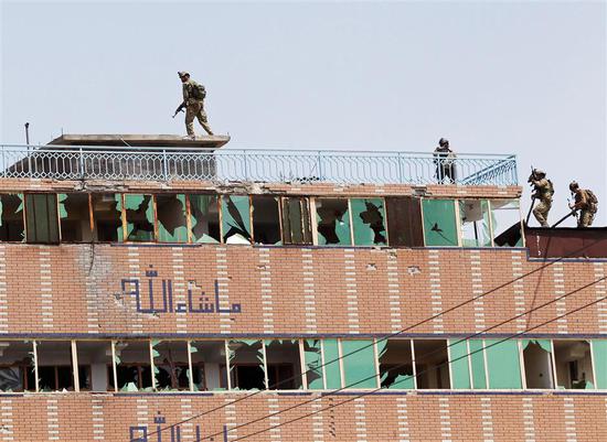  Afghan security forces take position on a building where the Islamic State militants were hiding after an attack on a jail compound in the city of Jalalabad on Monday.