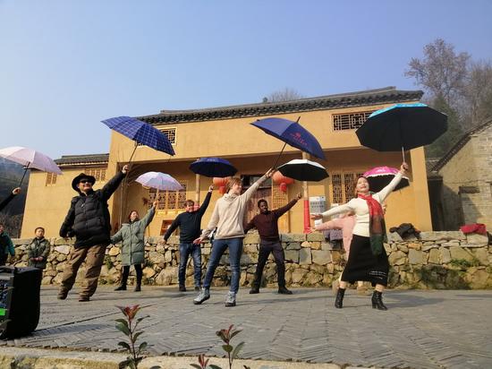 Michael Chick, Shaun Nish, Rebecca Nish, and Albert Mhangami dance with villagers at Dawan Village in Jinzhai County of Luan City, east China's Anhui Province, Dec. 19, 2020. (Xinhua/Liu Fangqiang)