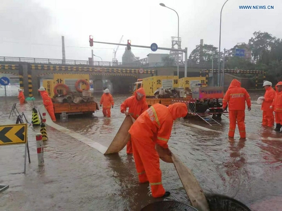 Staff members from Beijing Drainage Group drain water from a waterlogged street as rainstorms hit Shijingshan District in Beijing, capital of China, July 18, 2021. The Beijing Meteorological Observatory on Sunday morning issued an orange warning for rainstorms after the accumulated rainfall in some areas of the capital had exceeded 150 mm. (Xinhua)