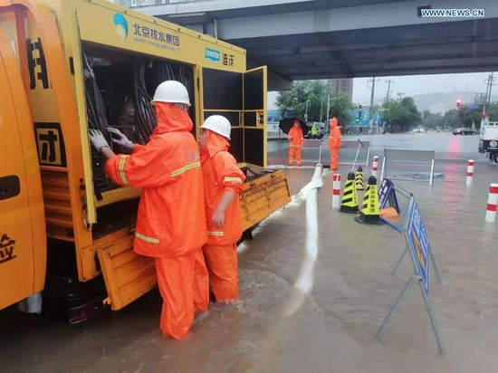 Staff members from Beijing Drainage Group drain water from a waterlogged street as rainstorms hit Shijingshan District in Beijing, capital of China, July 18, 2021. The Beijing Meteorological Observatory on Sunday morning issued an orange warning for rainstorms after the accumulated rainfall in some areas of the capital had exceeded 150 mm. (Xinhua)