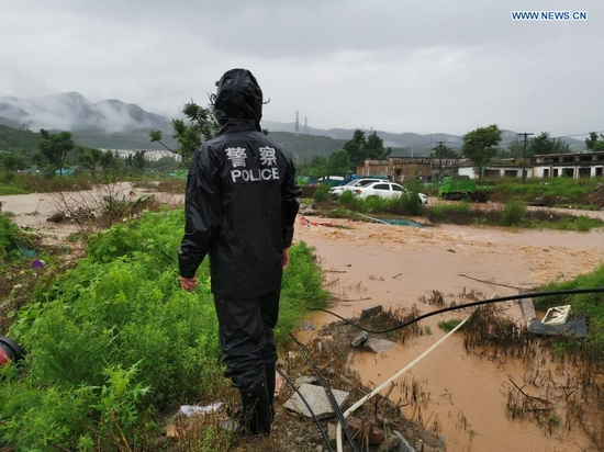  A police officer checks a road ruined by rainstorm-triggered flood in Mentougou District in Beijing, capital of China, July 18, 2021. The Beijing Meteorological Observatory on Sunday morning issued an orange warning for rainstorms after the accumulated rainfall in some areas of the capital had exceeded 150 mm. (Xinhua)