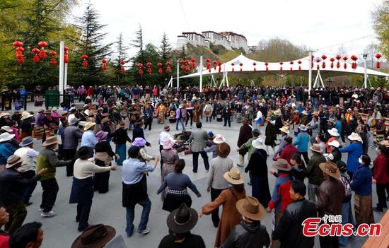 People perform a Guozhuang dance at a park near the Potala Palace in Lhasa, Southwest China’s Tibet Autonomous Region, Oct. 19, 2016. As one of the three major Tibetan folk dances, the Guozhuang dance involves 