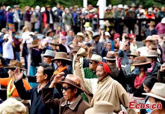 People perform a Guozhuang dance at a park near the Potala Palace in Lhasa, Southwest China’s Tibet Autonomous Region, Oct. 19, 2016. As one of the three major Tibetan folk dances, the Guozhuang dance involves 