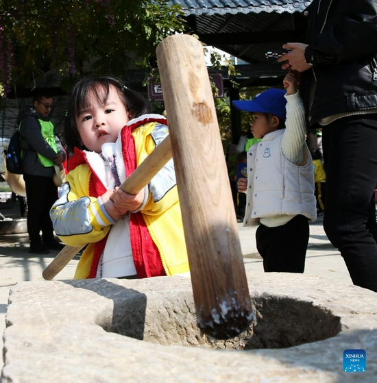 Photo taken on Nov. 27, 2021 shows children using a pestle and mortar at Zhaizi Farming Experience Centre in Qianjiang, southwest China's Chongqing Municipality. Qianjiang District established the farming experience centre to attract more children to the countryside, so that they can gain a practical understanding of farm labour and learn about crops and the history of agriculture. (Xinhua/Yang Min)