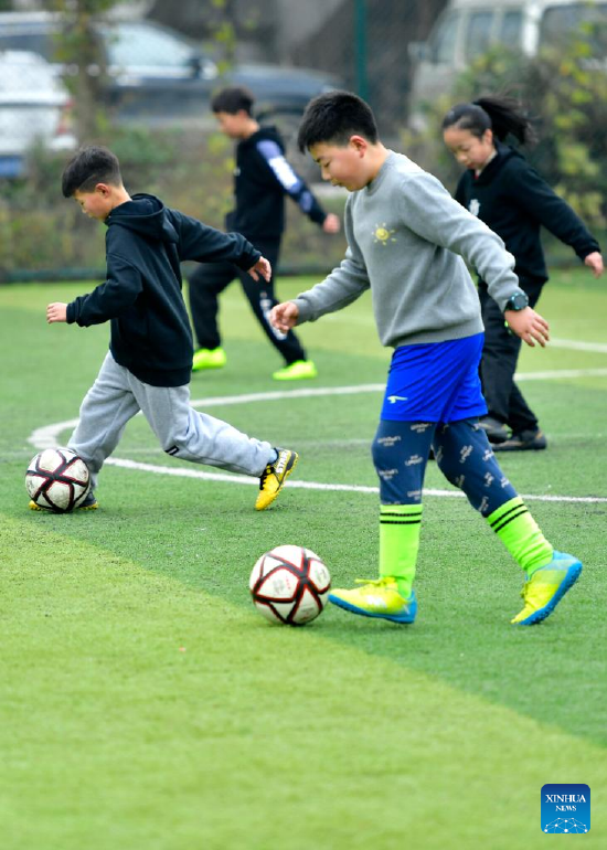 Pupils play football during winter vacation in Xuanen County, central China's Hubei Province, Jan. 18, 2022. (Photo by Song Wen/Xinhua)