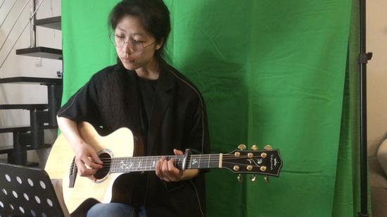 In this undated photo provided by herself, Qu Tianru records a guitar instruction video at home in Anshan, northeast China's Liaoning Province. (Xinhua)