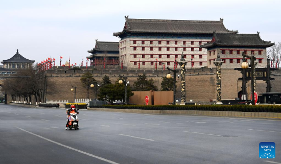 A deliveryman is seen on an empty street near Yongning Gate in Xi'an, northwest China's Shaanxi Province, Dec. 28, 2021. Authorities in Xi'an have upgraded epidemic control and prevention measures starting Monday, ordering all residents to stay indoors and keep away from gatherings except when taking nucleic acid tests. (Xinhua/Tao Ming)