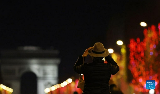 People take photos of the Champs-Elysees Avenue and the Arc de Triomphe amid Christmas illuminations in Paris, France, Nov. 21, 2021. The annual Christmas season lighting ceremony was held here on Sunday. (Xinhua/Gao Jing) 