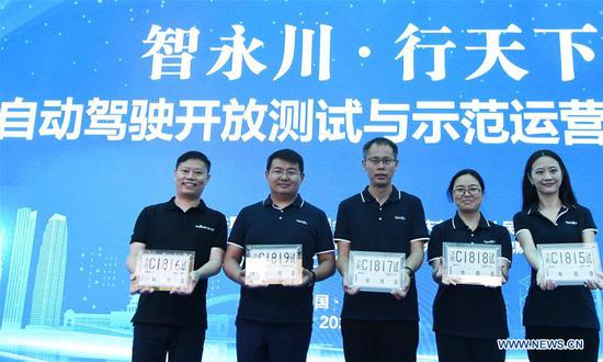 Staff members show the license plates to allow road tests for self-driving vehicles with passengers in southwest China's Chongqing Municipality, Sept. 17, 2020. A medium-sized bus equipped with autonomous driving technologies made its debut Thursday in Chongqing Municipality, a vehicle-manufacturing powerhouse in southwestern China. The L4 autonomous bus was a joint effort of Baidu Apollo and domestic bus manufacturer King Long. At the same time, Baidu obtained 10 license plates to allow road tests for self-driving vehicles with passengers issued by the municipal government. (Xinhua/Wang Quanchao)