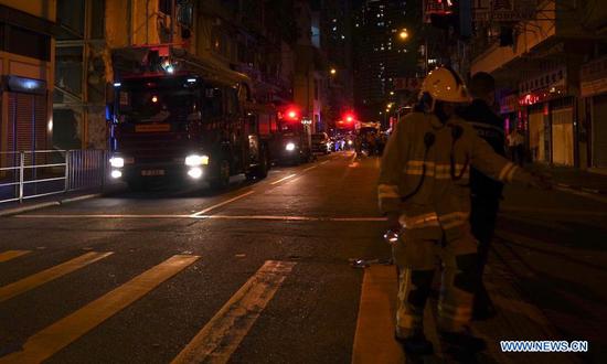 Fire fighters and police officers investigate a fire scene in Hong Kong, south China, Nov. 15, 2020. Seven people were killed and more than 10 others were injured after a fire broke out at a tenement building in Hong Kong on Sunday night, the police said.
