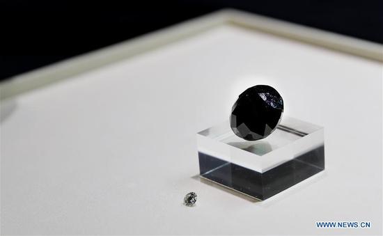 A black diamond weighing 88 carats is pictured next to a 5-carat diamond in Shanghai, east China, Oct. 26, 2020. With an estimated value of 37 million U.S. dollars, the diamond from Paris will be on display during the upcoming third China International Import Expo (CIIE) in Shanghai. (Xinhua/Fang Zhe)