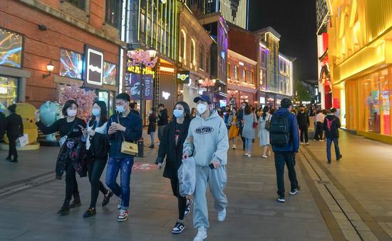 People walk on a commercial street in Wuhan, central China's Hubei Province, March 28, 2021. (Xinhua/Cheng Min)