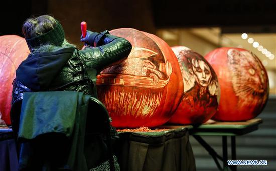 An artist carves a pumpkin at the Chicago Botanic Garden's Night of 1000 Jack-O'-Lanterns in Glencoe, Illinois, the United States, on Oct. 24, 2020. More than 1,000 hand-carved pumpkins are on display here pending Halloween. (Photo by Joel Lerner/Xinhua)