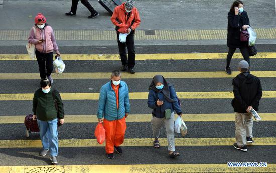 People wearing face masks walk across the street in south China's Hong Kong, Jan. 12, 2021. Hong Kong's Center for Health Protection (CHP) reported 60 additional confirmed cases of COVID-19 on Tuesday, taking its total tally to 9,343. All of the 60 new cases are local infections, with 13 of unknown origins. (Xinhua/Lo Ping Fai)