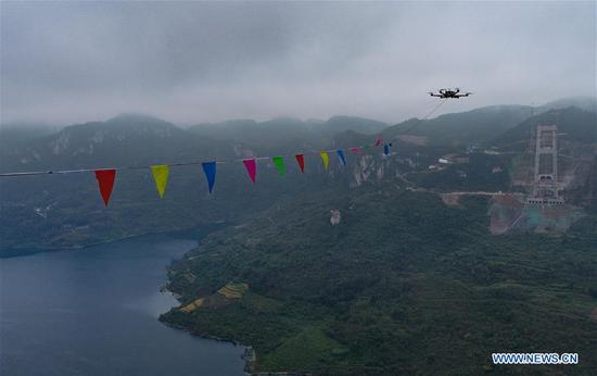 Aerial photo taken on Nov. 5, 2020 shows a drone carrying the pilot cable of a highway bridge under construction over the Kaizhou Lake in southwest China's Guizhou Province. The bridge is a part of the highway linking Weng'an and Kaiyang in Guizhou. After linking the pilot cable, the construction team will start to erect the main cable of the bridge. (Xinhua/Liu Xu) 