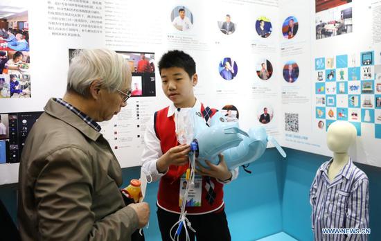 Wu Zengyang (R), a student from the Second School Affiliated to Fudan University, introduces his invention to a visitor during the 8th China (Shanghai) International Technology Fair (CSITF) in east China's Shanghai, April 15, 2021. The 8th CSITF kicked off on Thursday. With an exhibition area covering 35,000 square meters, this year's fair has 5 different sections and has attracted over 1,000 exhibitors. (Xinhua/Fang Zhe)