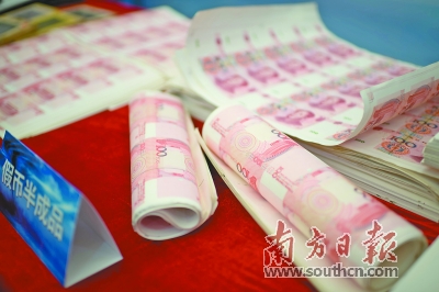 Police officers display half-made counterfeit bank notes at a press conference yesterday.