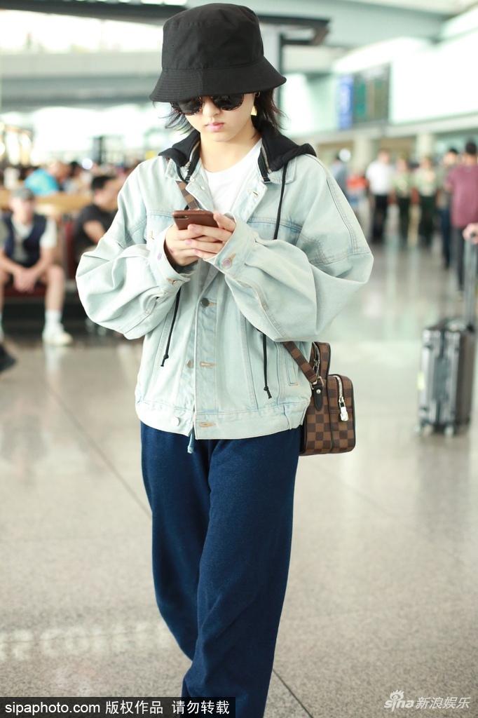 张子枫墨镜遮面休闲现身机场 一路低头专心玩手机