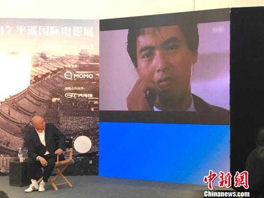 在大师班活动上,屏幕上播放着《英雄本色》的经典片段,吴宇森回头观看,这一幕令人唏嘘不已。 胡健 摄