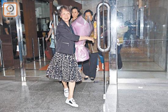 刘嘉玲的妈妈手拿鲜花笑得开心。