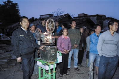2016年12月29日，广西钦州市钦北区板城镇，农民罗衍宗（左）在小董村放电影。图/视觉中国
