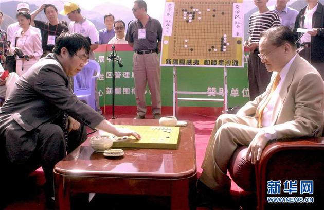 这是2001年8月5日，金庸（前右）与聂卫平（前左）在新疆天池畔对弈。 新华社记者 罗晓光 摄