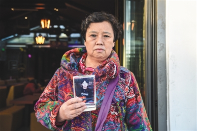 11月9日，北京什刹海公园，李艳霞手持儿子的照片在一家酒吧门前。实习生 湛超越 摄