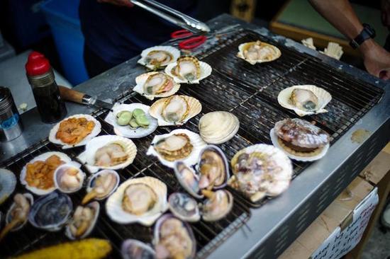 鱼市外的餐厅当场烹饪市场直采的海鲜，露天烧烤的扇贝和蛤蜊滋滋作响