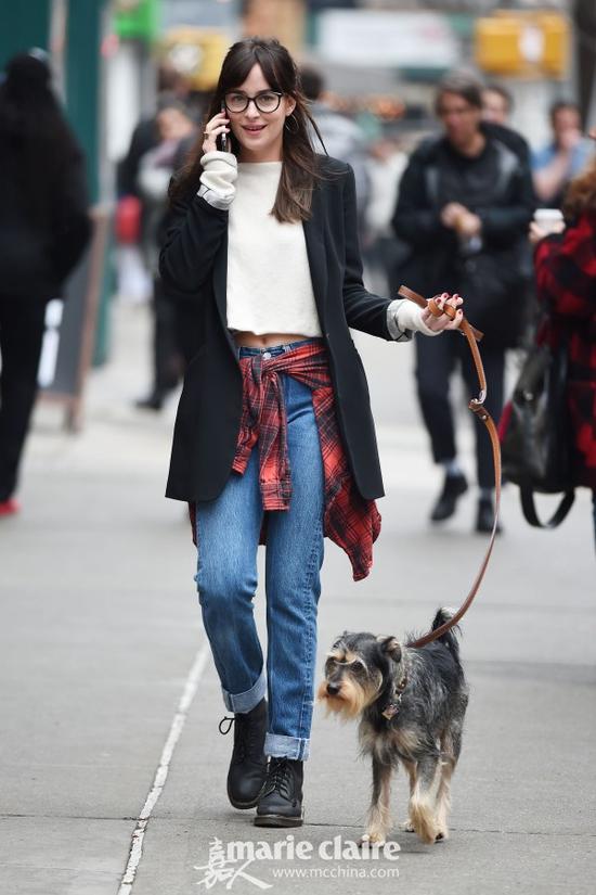 达科塔·约翰逊(DAKOTA JOHNSON)牵爱犬出街。达科塔·约翰逊佩戴黑框眼镜,身穿黑色西服,内搭白色短款针织衫,腰系红黑格纹衬衫,下配牛仔裤,脚踩黑色马丁靴。