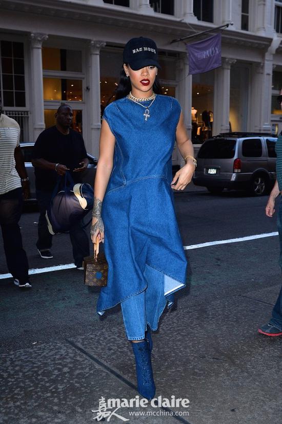 蕾哈娜(Rihanna)戴slogan棒球帽出街,她身穿牛仔无袖连衣裙,叠穿拼色牛仔裤,脚踩Manolo Blahnik牛仔质地系带踝靴,手提Louis Vuitton X Frank Gehry Twisted Box小包