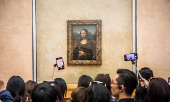 被众多游客环绕的名画《蒙娜丽莎》。图片来源:卫报。